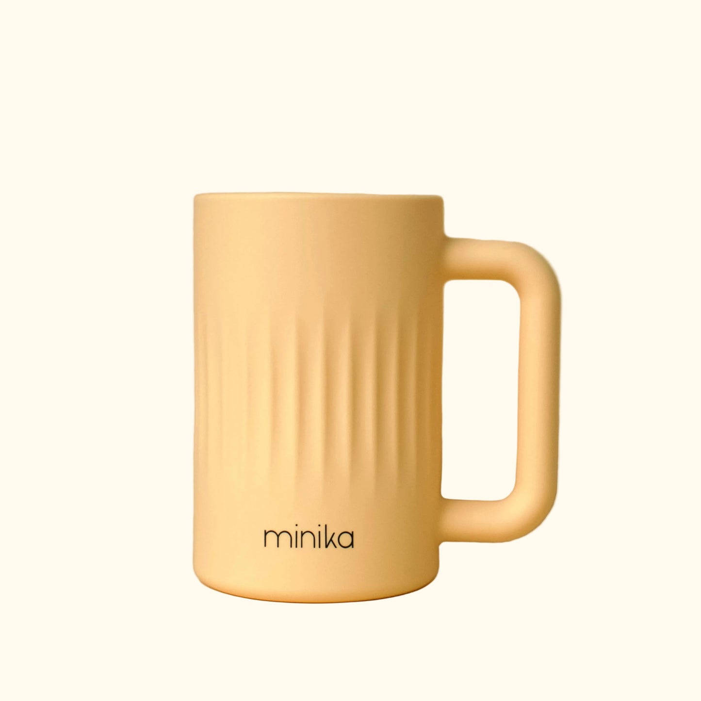 yellow mug with minika branding on a beige background
